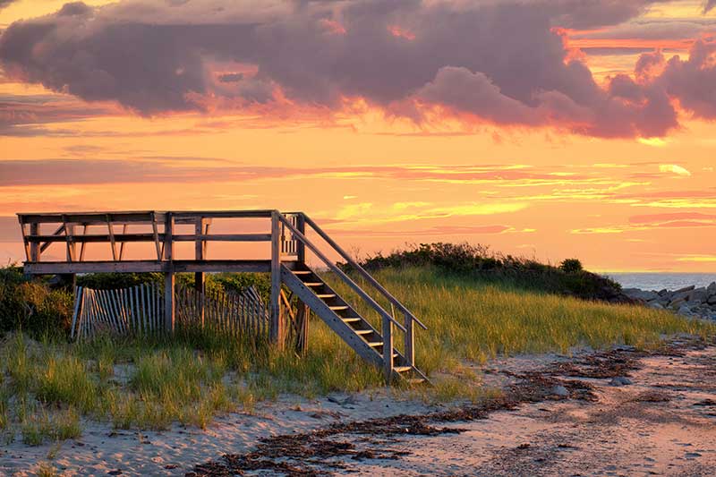 dennis massachusetts cannabis dispensary: Lovely Cape Cod beach scene with colorful sunlit clouds and sun about to drop below the horizon. Vibrant summer sunset captured at Corporation Beach in Dennis, Massachusetts.