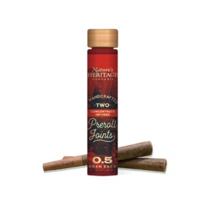 Tall red Nature's Heritage cannabis product bottle with a wooden cap, surrounded by cinnamon sticks; text on label reads 'Two' and '0.5 gram each'.